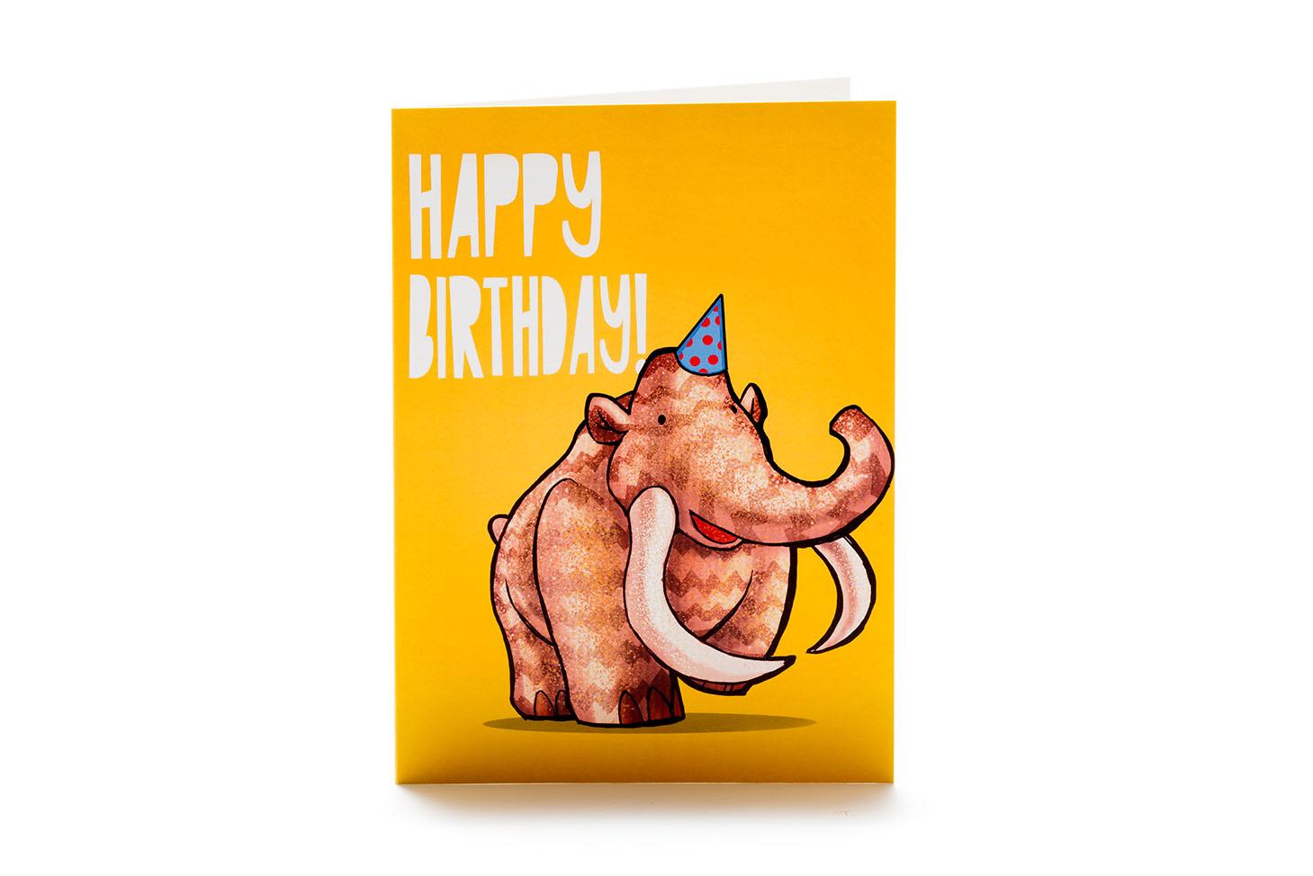 Orange greetings card featuring mammoth cartoon in party hat with happy birthday in white writing